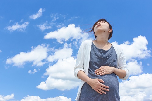 青空を見上げる妊婦